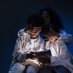 Mãe acompanha duas crianças enquanto elas usam um tablet, em uma cena de supervisão e segurança no ambiente digital.